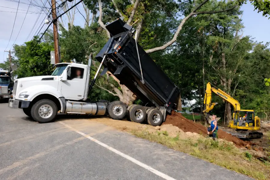 Dump truck placing fill while an excavator works nearby